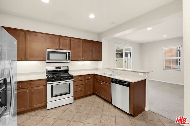 kitchen featuring sink, tasteful backsplash, kitchen peninsula, light colored carpet, and stainless steel appliances