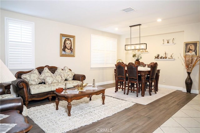 living room featuring recessed lighting, wood finished floors, visible vents, baseboards, and an inviting chandelier