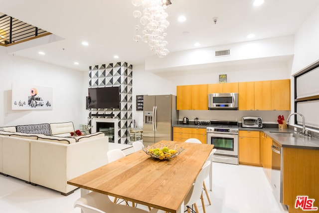 kitchen with an inviting chandelier, stainless steel appliances, a fireplace, and sink