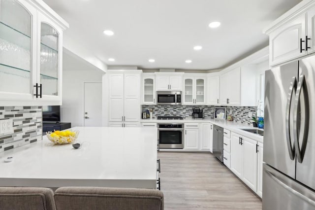 kitchen with sink, white cabinetry, tasteful backsplash, appliances with stainless steel finishes, and light hardwood / wood-style floors