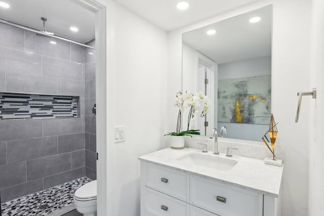 bathroom with vanity, toilet, and tiled shower