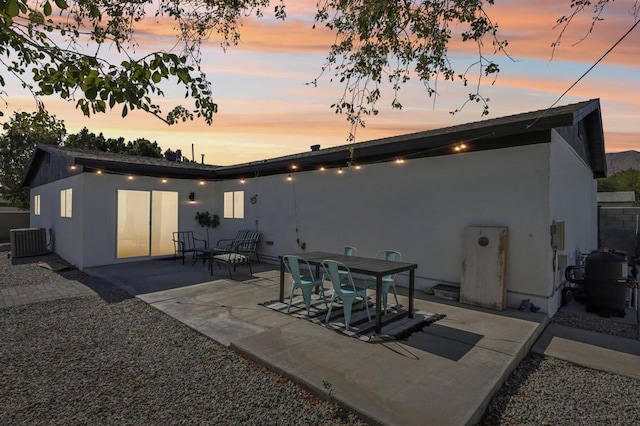 back house at dusk featuring a patio and central AC unit