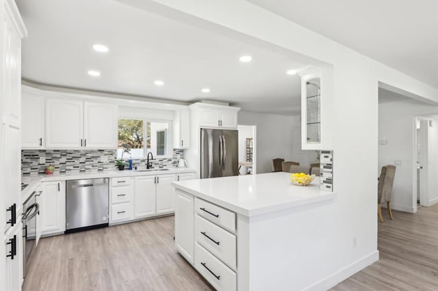 kitchen with sink, light hardwood / wood-style flooring, backsplash, stainless steel appliances, and white cabinets