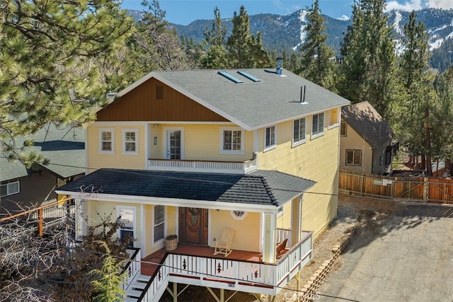 view of front facade with a shingled roof, fence, and a mountain view