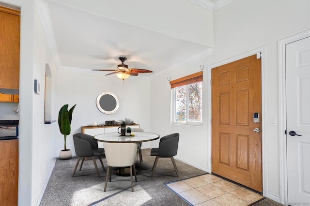 tiled dining room with ornamental molding and ceiling fan