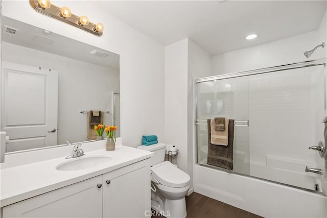 full bathroom featuring vanity, wood-type flooring, bath / shower combo with glass door, and toilet