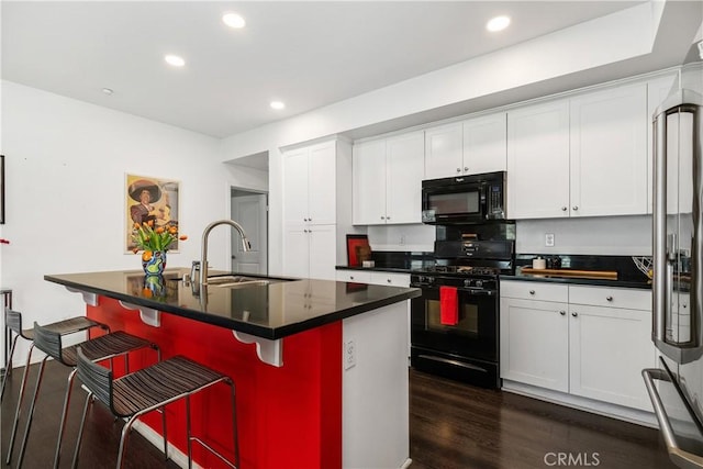 kitchen featuring white cabinetry, sink, a center island with sink, and black appliances