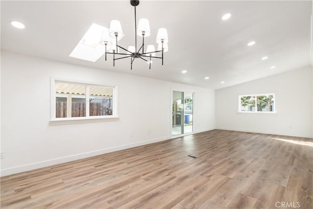 interior space featuring lofted ceiling with skylight and light hardwood / wood-style floors