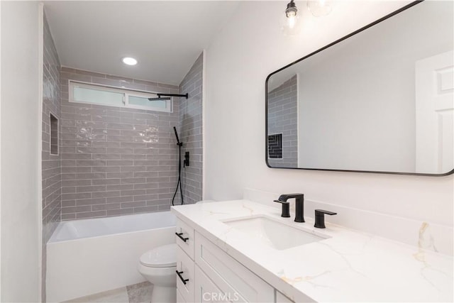 full bathroom with tiled shower / bath, vanity, and toilet