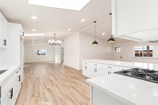 kitchen with light stone counters, vaulted ceiling, light hardwood / wood-style flooring, pendant lighting, and white cabinets