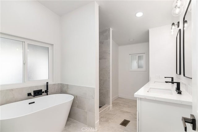 bathroom with vanity, separate shower and tub, and tile walls