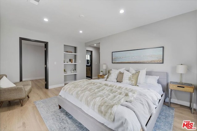 bedroom featuring a walk in closet and light hardwood / wood-style floors