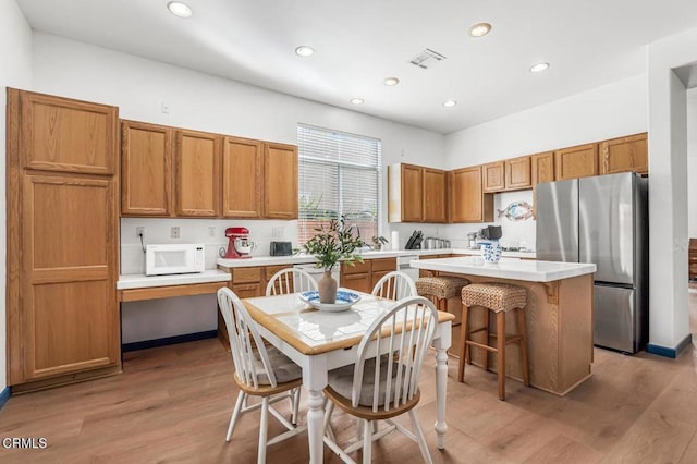 kitchen with stainless steel appliances, a center island, a breakfast bar, and light hardwood / wood-style floors