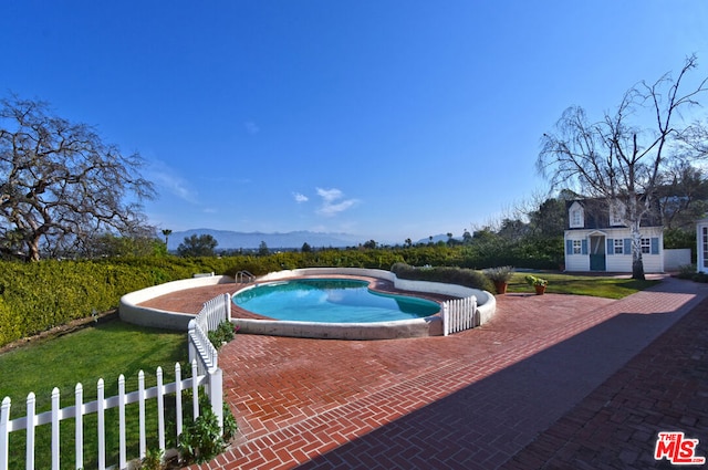 view of pool featuring a mountain view, an outdoor structure, and a patio