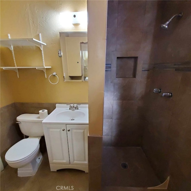 bathroom with tiled shower, vanity, toilet, and tile patterned flooring