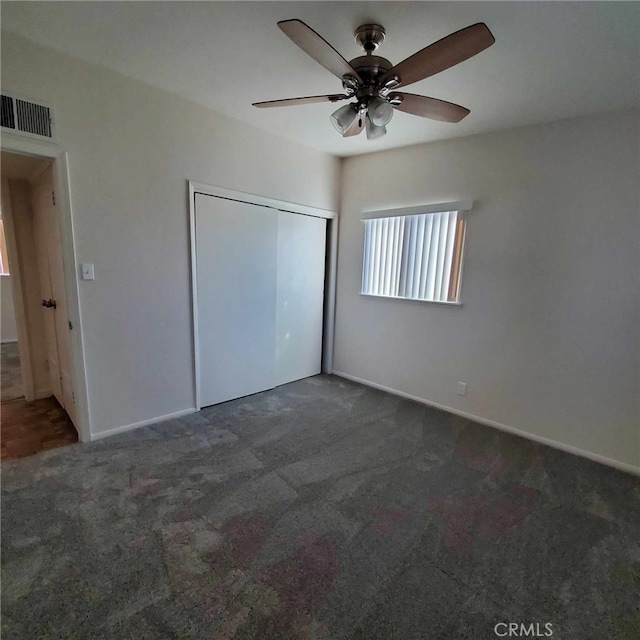 unfurnished bedroom featuring dark colored carpet, ceiling fan, and a closet