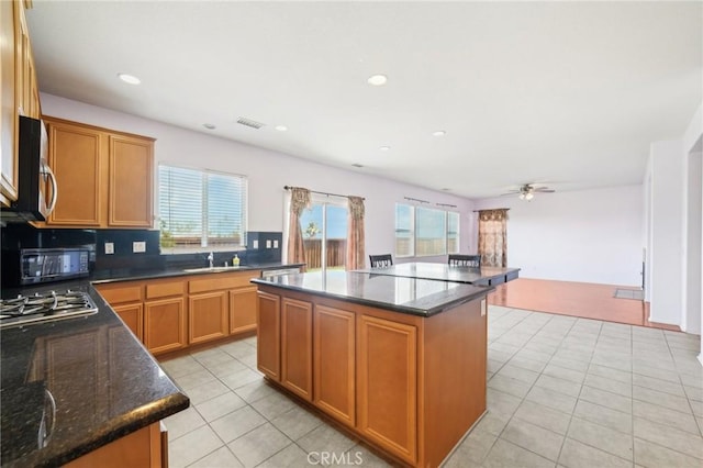 kitchen with a kitchen island, a healthy amount of sunlight, dark stone countertops, and appliances with stainless steel finishes