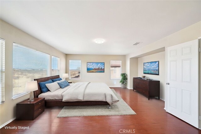 bedroom with multiple windows and dark hardwood / wood-style floors