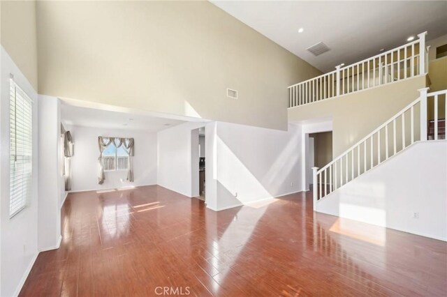 unfurnished living room with hardwood / wood-style flooring and a high ceiling