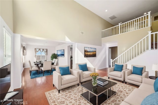 living room featuring a towering ceiling and hardwood / wood-style floors