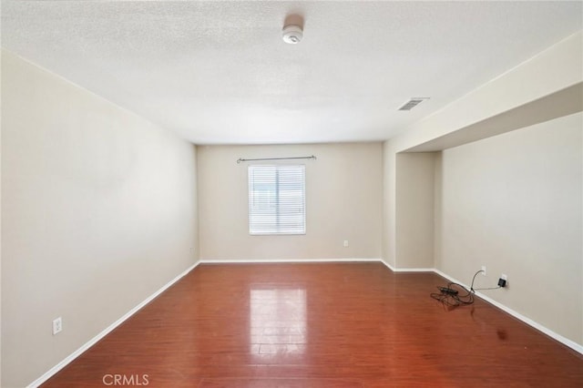 spare room featuring wood-type flooring and a textured ceiling