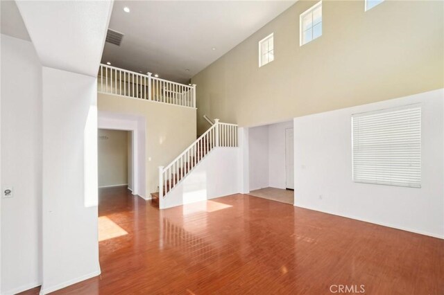 spare room with a towering ceiling and hardwood / wood-style floors