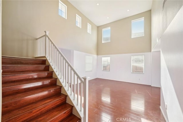 staircase with hardwood / wood-style flooring and a high ceiling