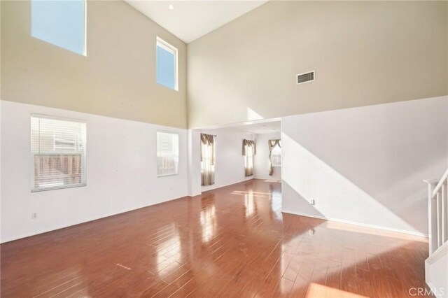 unfurnished living room with hardwood / wood-style flooring and a high ceiling