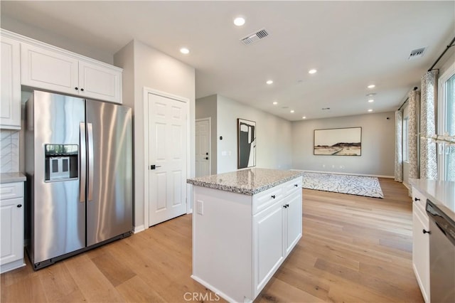 kitchen featuring stainless steel appliances, white cabinetry, a kitchen island, and light hardwood / wood-style floors