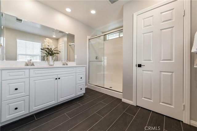 bathroom featuring vanity, a shower with shower door, and a healthy amount of sunlight