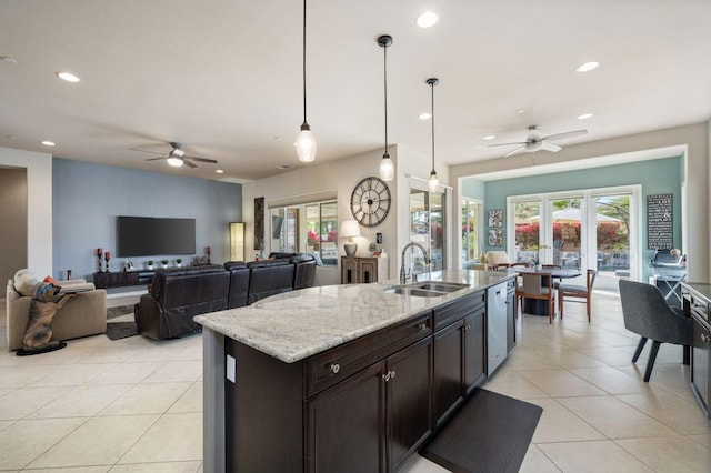 kitchen with sink, dishwasher, hanging light fixtures, dark brown cabinets, and light stone countertops