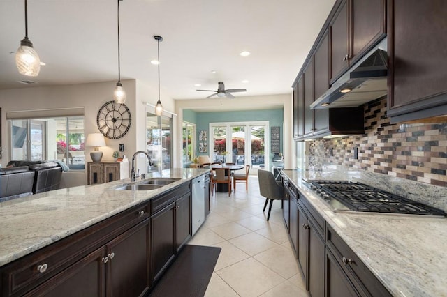 kitchen featuring light stone counters, stainless steel appliances, sink, and hanging light fixtures