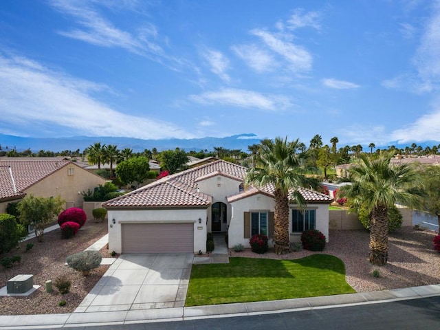 mediterranean / spanish house with a garage, a mountain view, and a front lawn