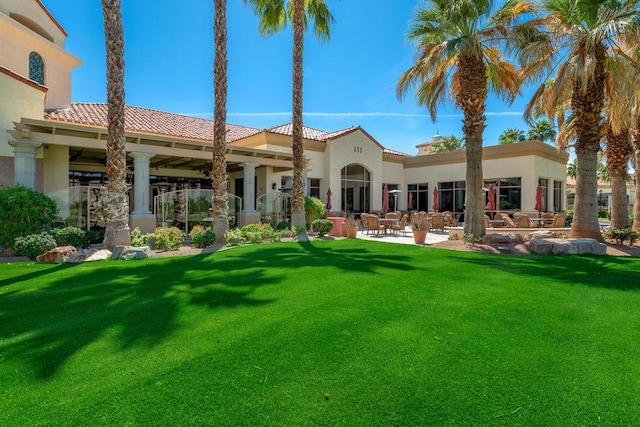 back of house with a patio and a lawn