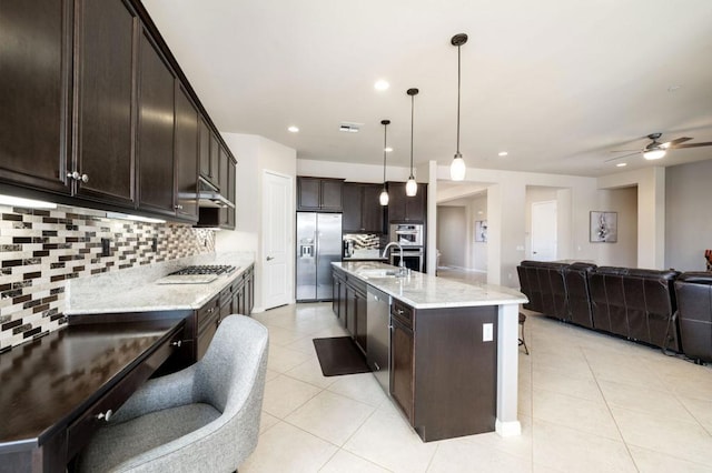 kitchen featuring dark brown cabinetry, sink, decorative light fixtures, a center island with sink, and appliances with stainless steel finishes