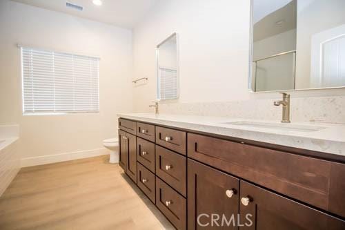 bathroom with hardwood / wood-style flooring, vanity, a bathing tub, and toilet