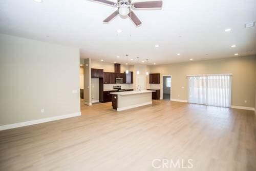 unfurnished living room featuring ceiling fan and light hardwood / wood-style flooring