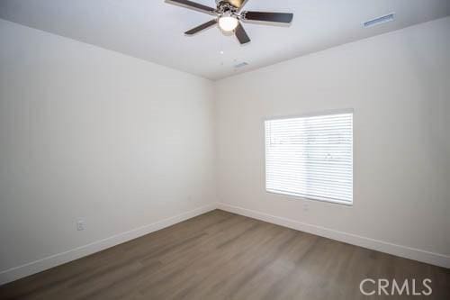 spare room with dark wood-type flooring and ceiling fan