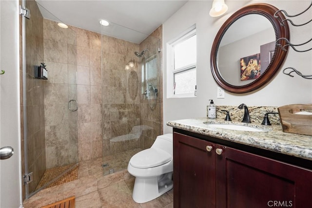 bathroom featuring vanity, a shower with door, and toilet