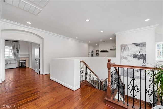 hallway with ornamental molding, a healthy amount of sunlight, and hardwood / wood-style floors