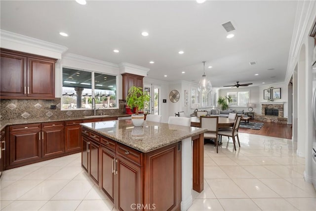 kitchen with crown molding, sink, light tile patterned floors, and a kitchen island