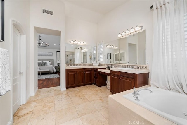 bathroom with tile patterned floors, vanity, tiled tub, and a towering ceiling