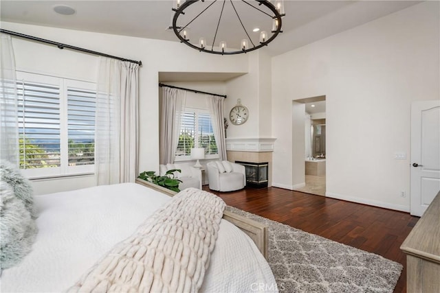 bedroom with dark wood-type flooring, a fireplace, and a notable chandelier