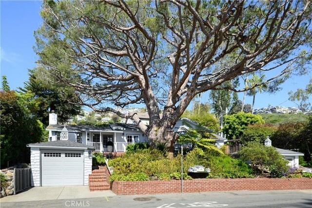 2130 Glenneyre St, Laguna Beach, CA 92651 - view of property hidden behind natural elements with a garage, covered porch, a chimney, stairway, and driveway