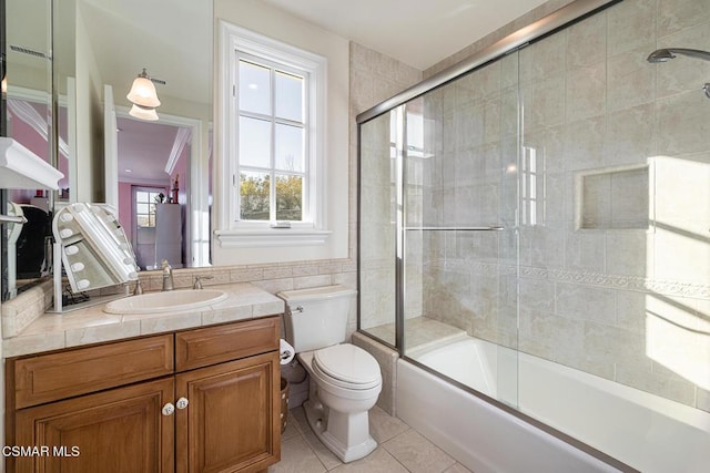 full bathroom with enclosed tub / shower combo, tile patterned flooring, tile walls, vanity, and toilet