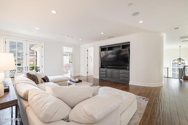 living room with french doors, ornamental molding, dark hardwood / wood-style flooring, and a notable chandelier