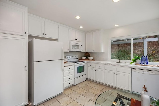 kitchen featuring light tile patterned floors, white appliances, sink, white cabinetry, and tile countertops