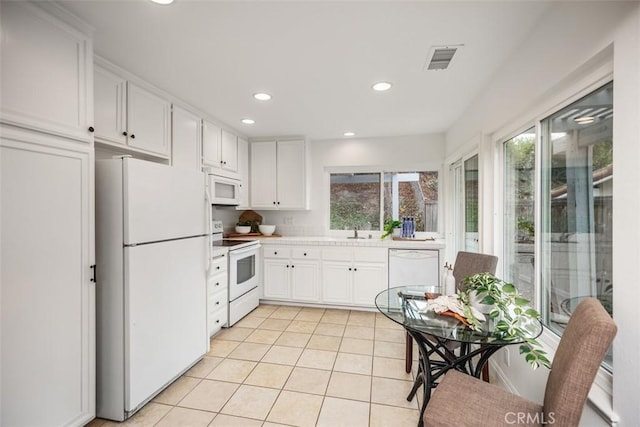 kitchen with white cabinetry, light tile patterned floors, white appliances, and sink