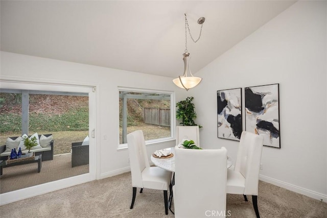 carpeted dining room featuring vaulted ceiling