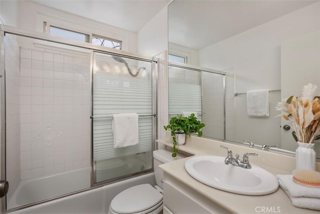 full bathroom featuring vanity, shower / bath combination with glass door, toilet, and a healthy amount of sunlight